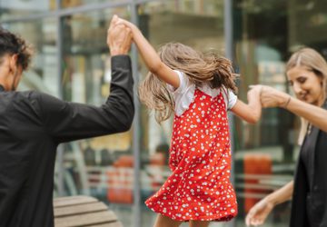 A child in a red dress with their parents