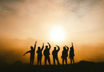 Silhouette of six people posing against a sunset