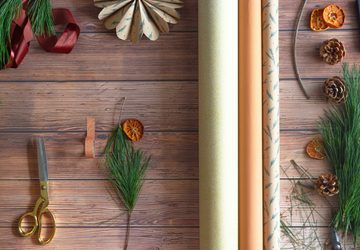 Neutral wrapping paper with Christmas tree branches and gold scissors