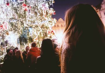 Person looking up at decorated outdoor Christmas tree