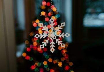White wooden snowflake decoration lit up by multi-coloured lights